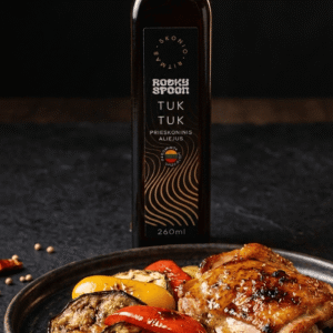 Rocky Spoon Tuk Tuk prieskoninis aliejus patiekiamas su kepta mėsa ir daržovėmis / Rocky Spoon Tuk Tuk spiced oil served with grilled meat and vegetables on dark background